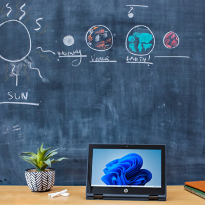 A laptop on a table displaying a blue object with text 'EARTH' and 'SUN'.