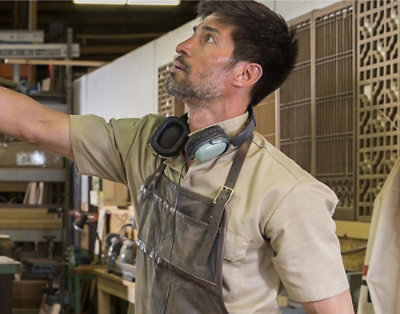A man wearing headphones and an apron pointing at something.