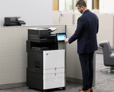 A black and white printer and a man standing Infront of it.