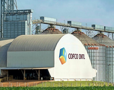 A large white building with a logo COFCO INTL PE and a green field in the background.