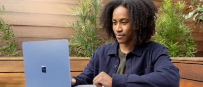 A curly haired man looking at the laptop and smiling