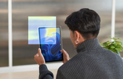 Person holding and viewing a tablet indoors.