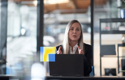Person speaking during a video call on a laptop in an office.