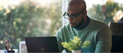 A man in a t shirt working on a laptop.