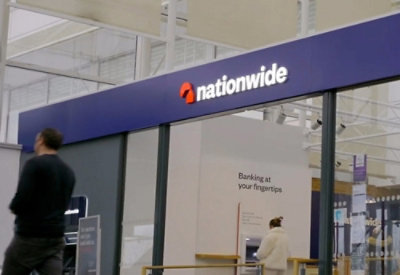 A person walks past a sign with text that says Nationwide Banking at your fingertips.