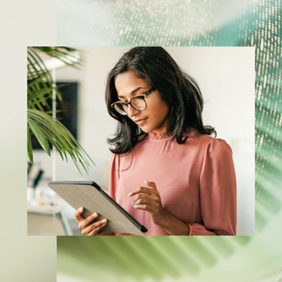 A women wearing glasses and looking focused while using tablet.