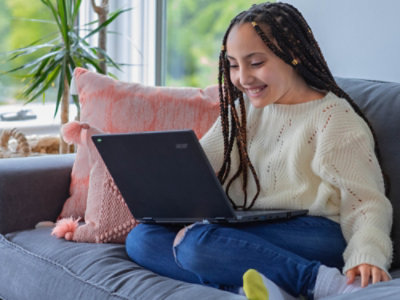 A child sitting on a couch using a computer.
