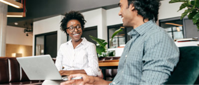 A person and another person looking at each other while working on laptop