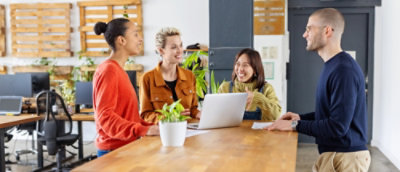 People collaborating around a laptop in a modern office workspace.