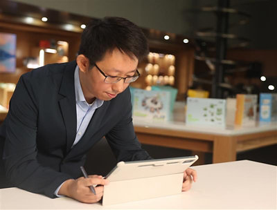A man in a suit writing on a tablet.