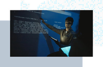 Person presenting technical information while pointing to code projected on a large screen.
