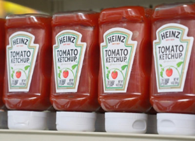 A row of Heinz tomato ketchup bottles on a shelf.