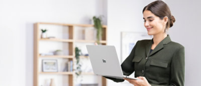 A person sitting at a desk holding a laptop.