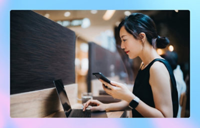 A woman using a laptop and a phone.