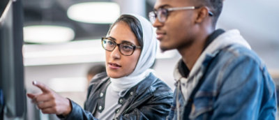 A woman wearing glasses and a scarf looks at something.