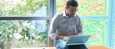 A man in an collared shirt sitting and using a laptop.