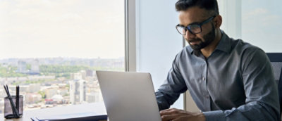 A man wearing specs working on the laptop