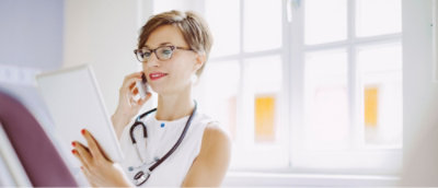A woman with short hair wearing glasses talking on a cell phone.