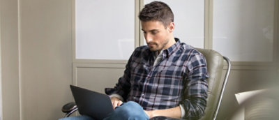 A person sitting in a chair using a laptop.
