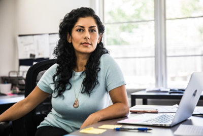 A women sitting at a table using a laptop.