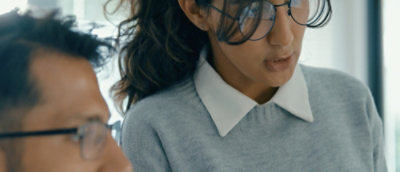 A women and a man wearing spects and looking somewhere.