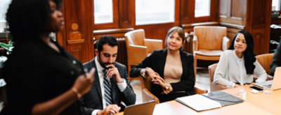 A group of people sitting around a table and discussing.
