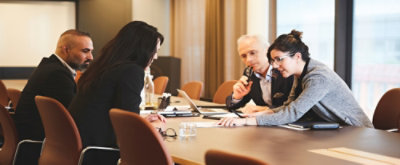 A group of people sitting around the table and looking at each other and discussing