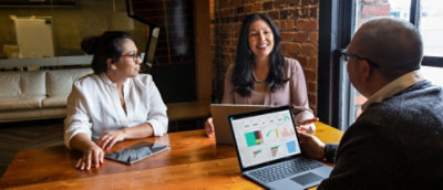 Group of three people having conversation with laptop open