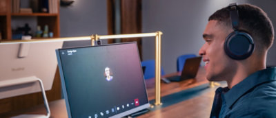 Person wearing headphones participating in a video call at a desk.