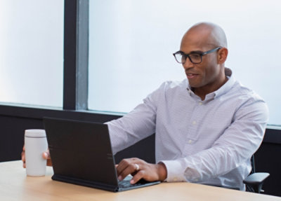 Person working on laptop at desk with coffee