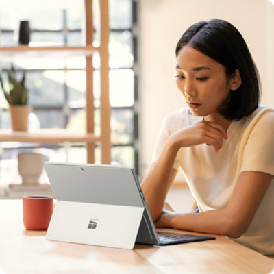 Een persoon die aan een tafel zit en werkt aan een Surface Pro voor zakelijk gebruik, die is aangesloten op een Surface Pro 13-inch Flex-toetsenbord voor zakelijk gebruik.