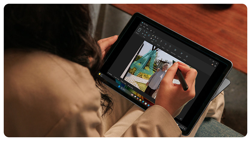 En person bruger en Surface Slim Pen til at redigere et familiefoto på en Surface Pro.