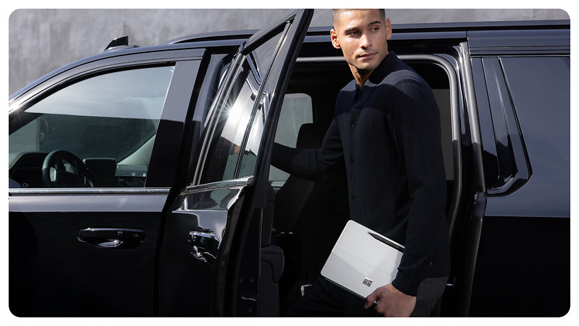 Uma pessoa segura um Surface Pro para Empresas enquanto sai de um carro.