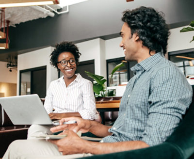 man and women taking notes and smiling while seated together in a bright office.