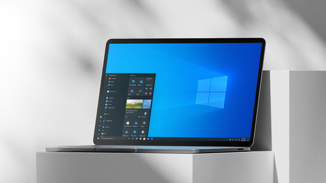 Ordinateur portable sur un pilier blanc ouvert sur l’écran d’accueil de Windows 10.