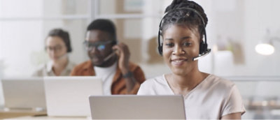 A woman wearing a headset is working on a computer.