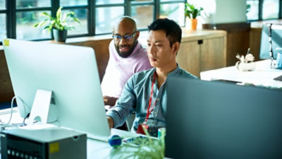 Two men sitting and looking at a laptop