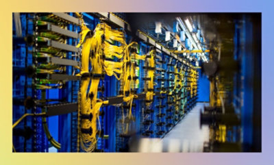 A row of server racks in a data center with organized yellow cables and blue lighting.