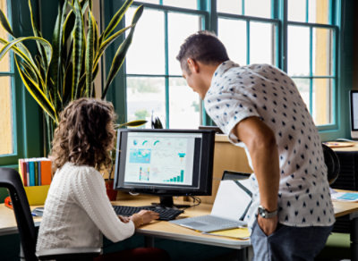 A man and woman looking at a computer screen.